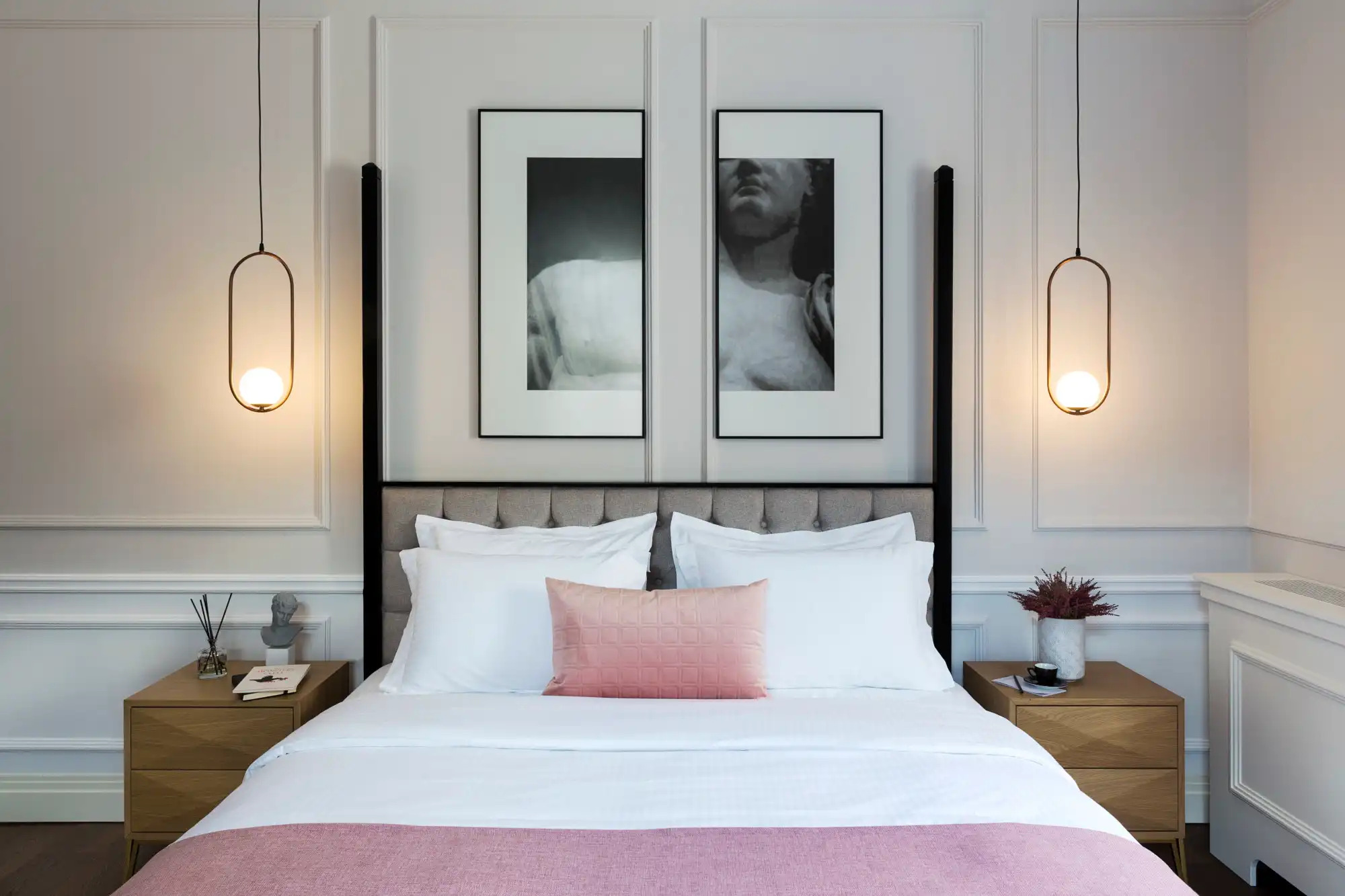 Modern hotel room with pink bedding, minimalist design, and contemporary artwork